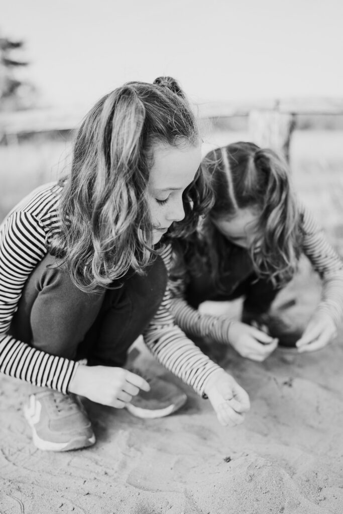 Familienfotograf Ludwigshafen: Zwei Mädchen entdecken gemeinsam Dinge im Sand – spielerisches Familienshooting