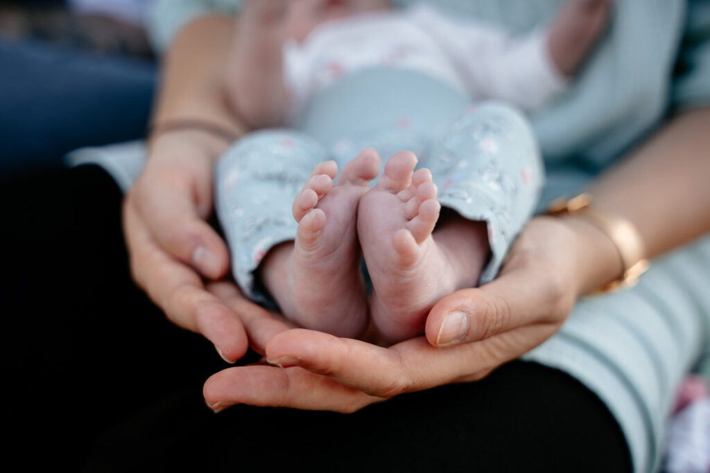 Babyfotos: Zarte Babyfüße in liebevollen Händen – symbolischer Moment