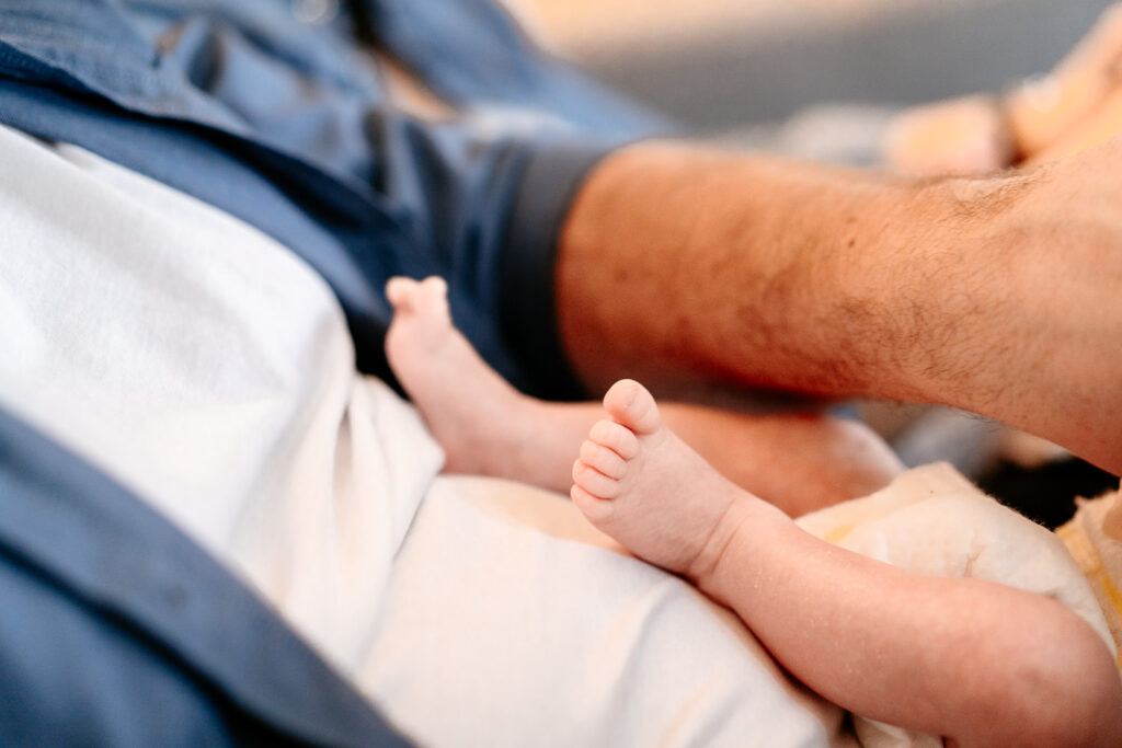 Babyfotos Frankfurt: Baby liegt entspannt auf Papas Bauch – Fokus auf die winzigen Babyfüße