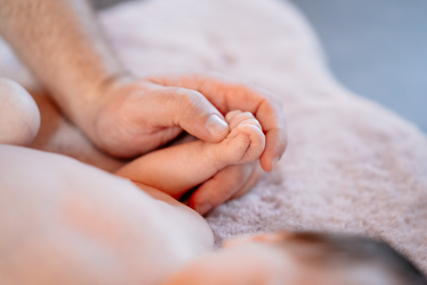 Babyfotos: Papa streichelt sanft die kleine Hand seines Babys – inniger Moment“