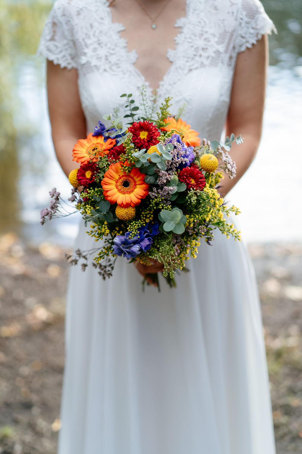 Hochzeitsfotografin fängt besondere Details ein: Braut hält ihren Brautstrauß elegant vor dem Bauch