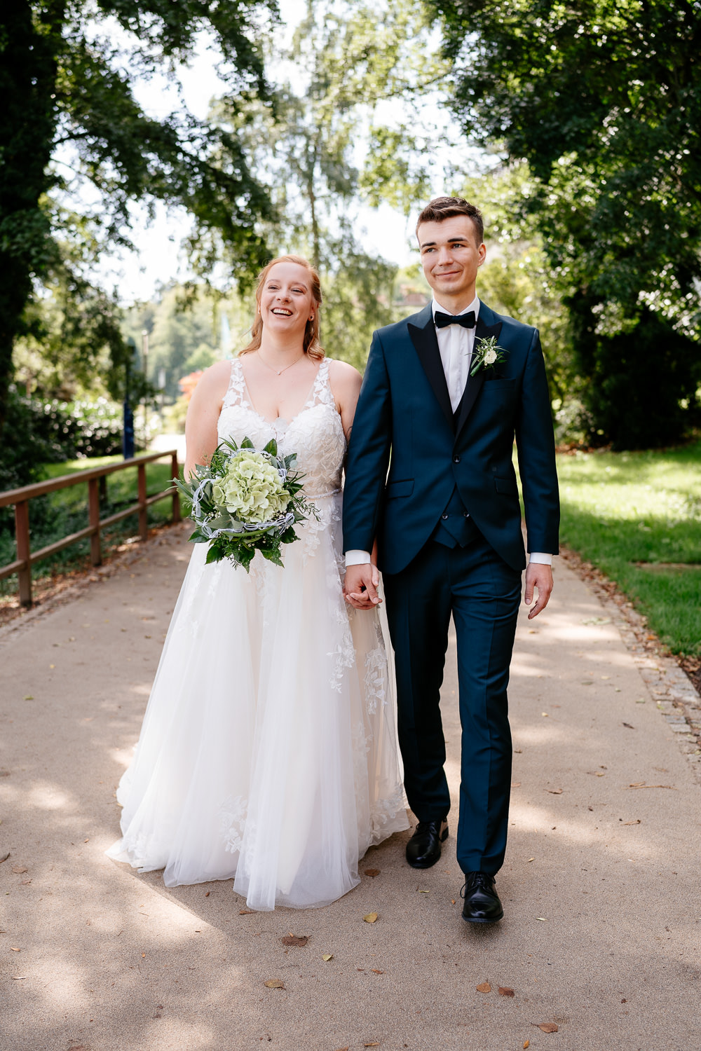 Hochzeitsfotos: Hochzeitspaar läuft Hand in Hand im Park