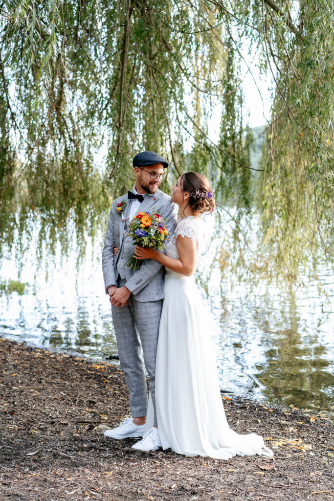 Hochzeitsfotografin Karlsruhe fängt emotionale Hochzeitsfotos ein: Die Braut hält den Bräutigam liebevoll im Arm, beide schauen sich an