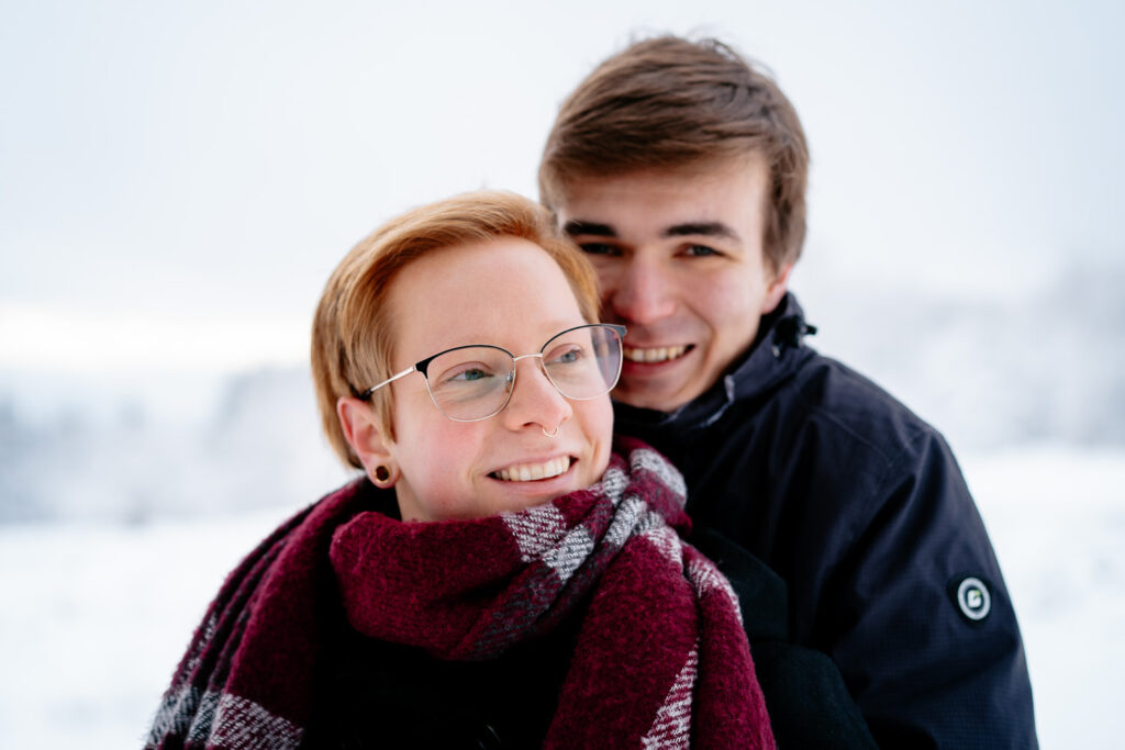 Pärchenfotografie: Portraitaufnahme eines Pärchens im Winter – er steht schützend hinter ihr